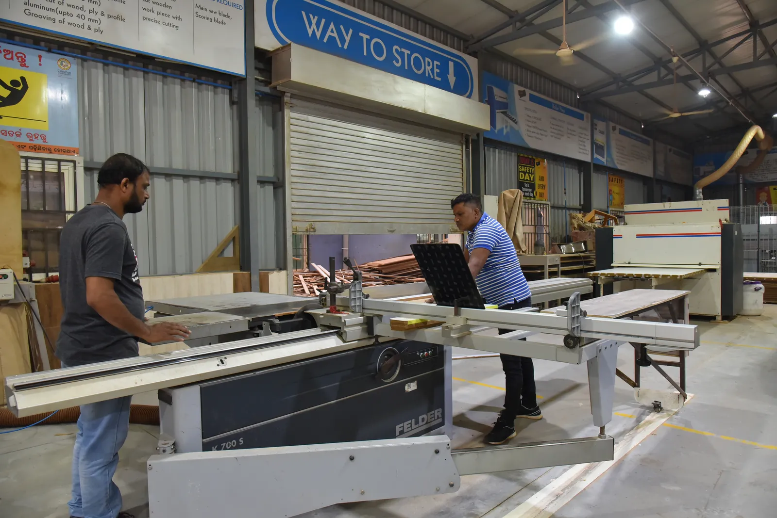 An instructor and trainee operating a Felder panel saw in the wood engineering centre